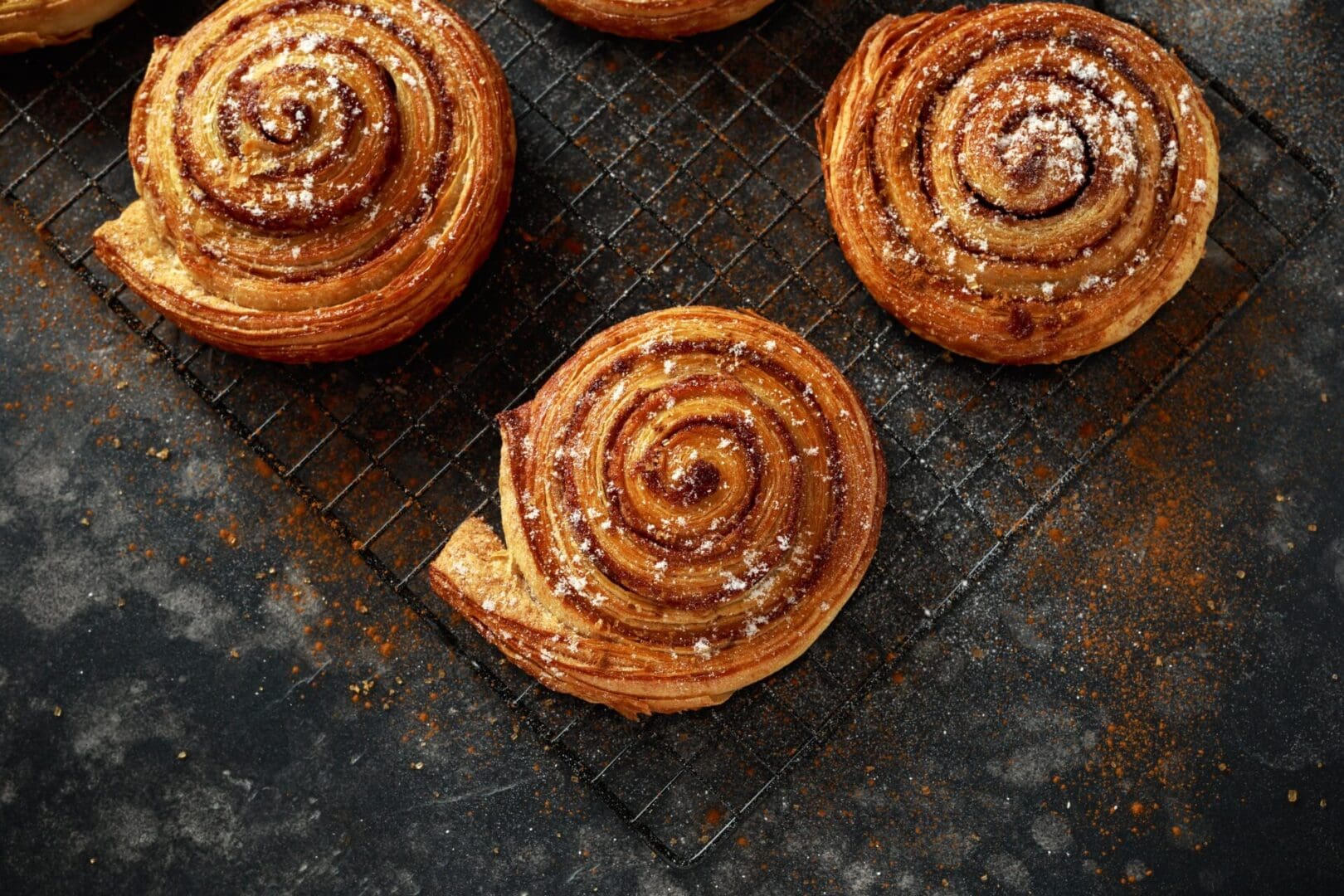 A close up of some cinnamon rolls on a cooling rack