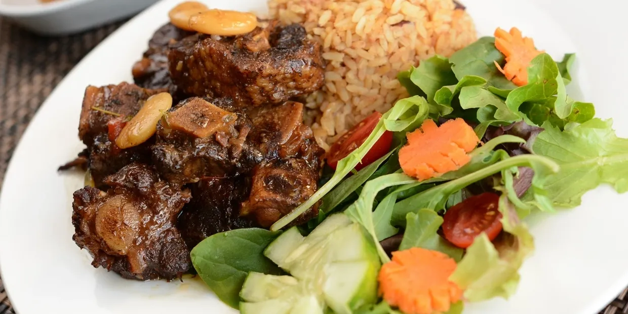 A plate of food with meat, rice and vegetables.